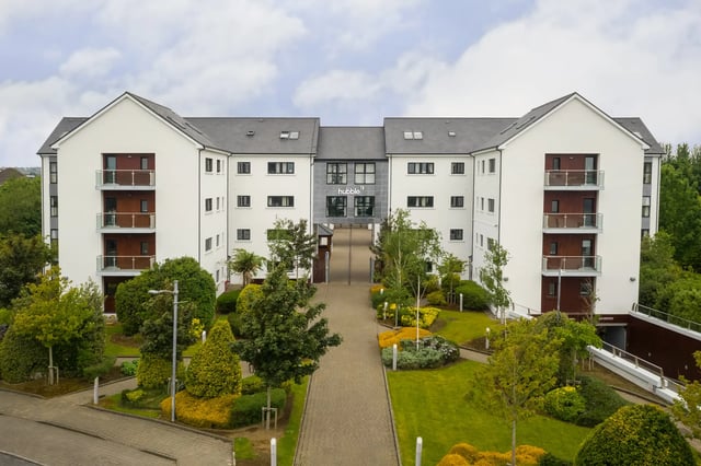 White building with balconies and green courtyard exterior at Cuirt na Coiribe in Galway Student Accommodation