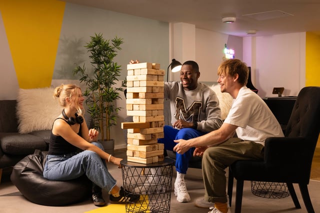 Friends play giant Jenga in common room living room at Joseph Stones House in Leeds Student Accommodation
