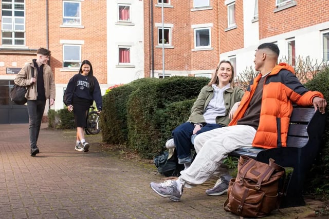 Students chatting on bench near building exterior at Westhill Hall in Sheffield Student Accommodation