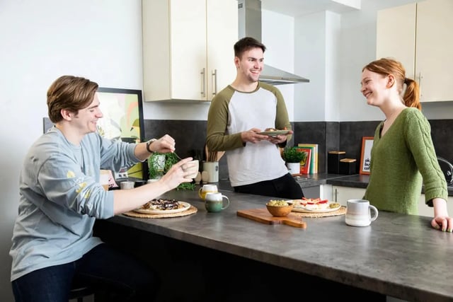 Three students chatting and eating in kitchen kitchen at Westhill Hall in Sheffield Student Accommodation