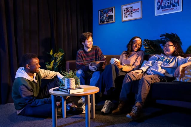 Four friends relaxing on sofa with popcorn living room at Westhill Hall in Sheffield Student Accommodation