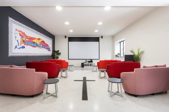 Red and pink sofas projector screen artwork lounge at St Vincents Place in Sheffield Student Accommodation