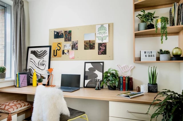Desk with laptop plants artwork and corkboard study area at Moonraker Point in London Student Accommodation