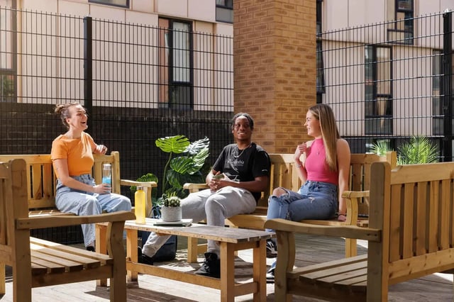 Students sitting on benches on outdoor patio exterior at Quay Point Studios in Newcastle Upon Tyne Student Accommodation