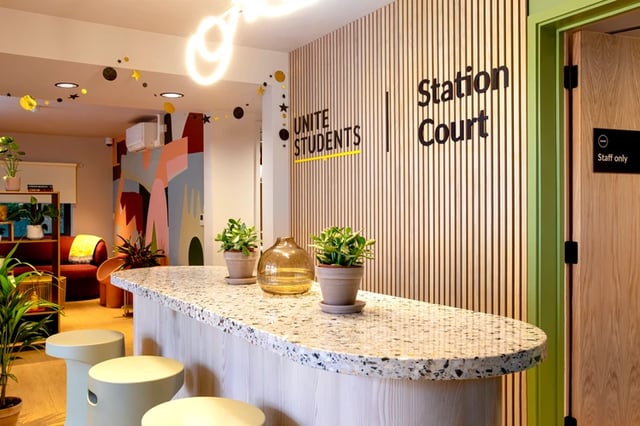 Reception desk plants stools and mural reception area at Station Court in London Student Accommodation
