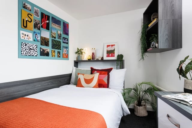 Bed with orange throw and decorative wall art bedroom at Hepworth Lodge in Leeds Student Accommodation
