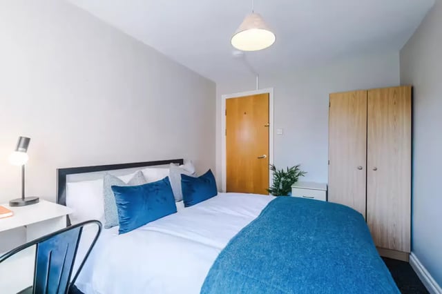Bed with blue pillows and desk bedroom at Chancellor's Court in Manchester Student Accommodation