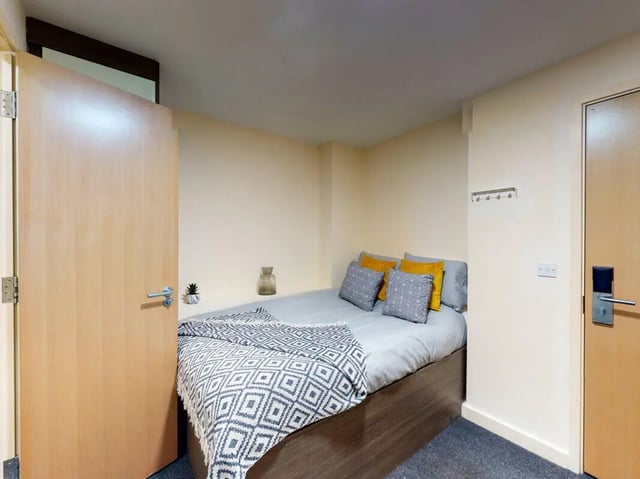 Bed with pillows throw and vase bedroom at The Cube in Bolton Student Accommodation