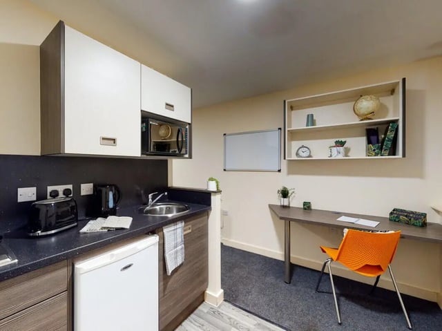 Kitchen with microwave sink fridge study area with desk chair at The Cube in Bolton Student Accommodation