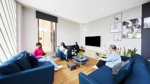 Four people on blue sofas near TV living room at Tudor Place in Chester Student Accommodation
