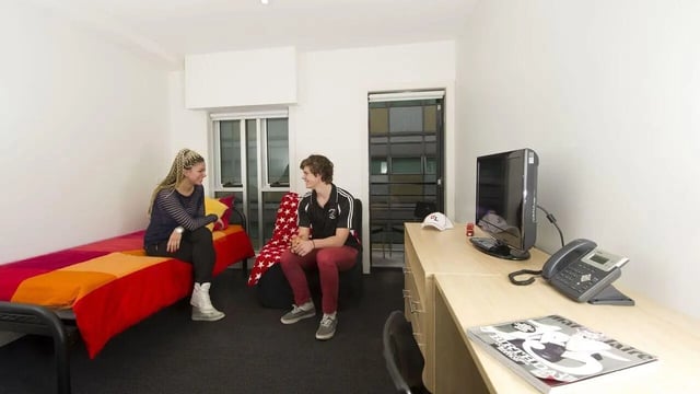 Two people bed desk and telephone Bedroom at Student Living - 740 Swanston in Melbourne Student Accommodation