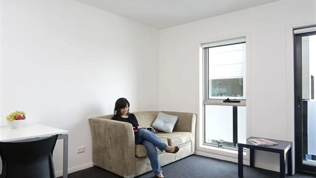Couch desk window woman reading living room at Student Living - 740 Swanston in Melbourne Student Accommodation