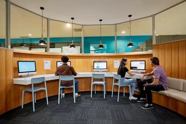 Students using computers at a curved study area at Scape Tribune in Brisbane Student Accommodation