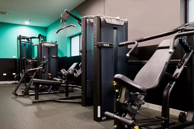 Gym machines with black upholstery and turquoise walls gym at Scape Tribune in Brisbane Student Accommodation