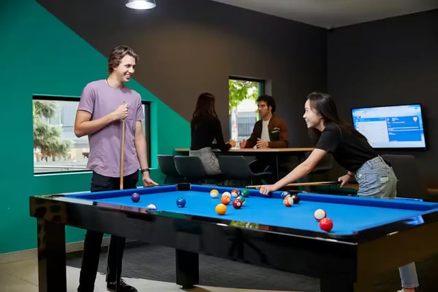 Students play billiards at a pool table playing area at Scape Tribune in Brisbane Student Accommodation