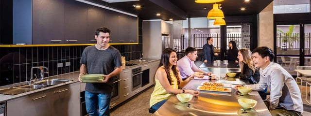People eating and cooking in modern kitchen area at Student One Adelaide Street in Brisbane Student Accommodation