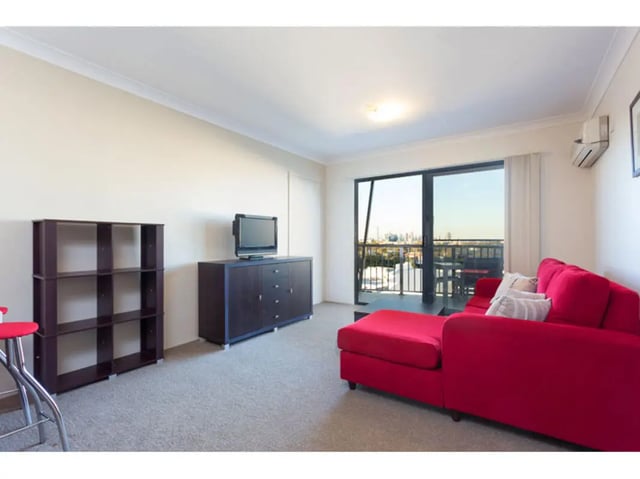 Red sofa tv console bookshelf living room at Altitude Taringa in Brisbane Student Accommodation