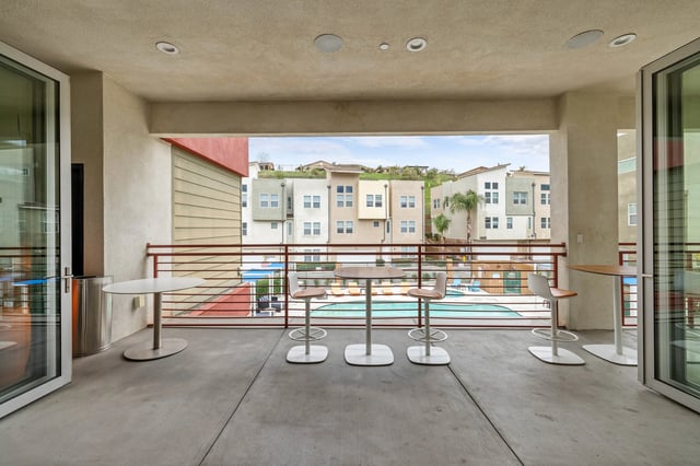 Balcony with tables chairs overlooking pool exterior at The Glen in San Bernardino Student Accommodation