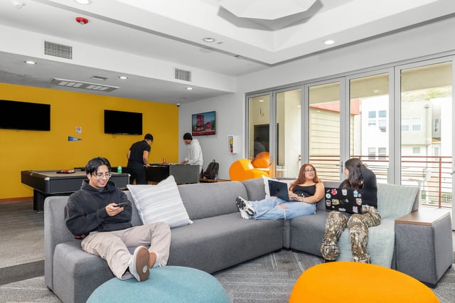 Students playing pool and relaxing on sofa living room at The Glen in San Bernardino Student Accommodation