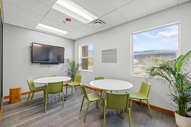 Four green chairs white tables wall mounted television study room at The Glen in San Bernardino Student Accommodation