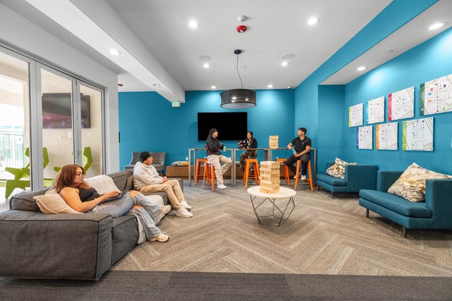 Students relaxing on couches near tables and game living room at The Glen in San Bernardino Student Accommodation