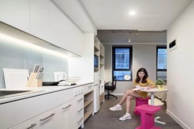Modern kitchen with young woman studying living room at Student One Elizabeth Street in Brisbane Student Accommodation