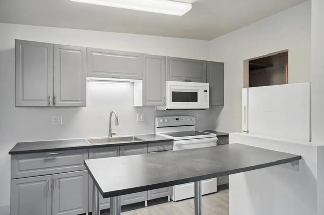 Gray cabinets microwave stove sink island kitchen at Tiltn Hiltn Apartments in Eagle Student Accommodation