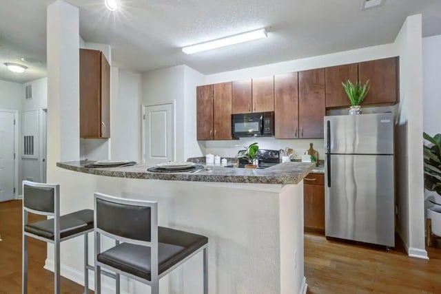 Two bar stools counter with plates refrigerator kitchen at The Union Charlotte in Charlotte Student Accommodation