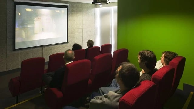 Students watching movie in red chairs cinema room at Student Living Auckland in Auckland Student Accommodation