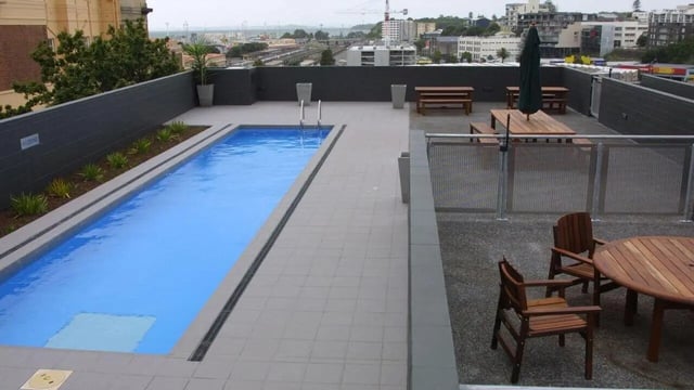 Rooftop pool with wooden tables and chairs. Exterior. at Student Living Auckland in Auckland Student Accommodation