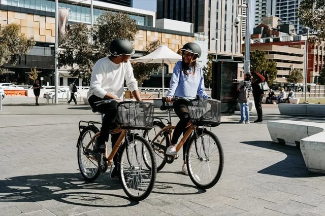 Two people cycling on city street exterior at Perth Central in Perth Student Accommodation