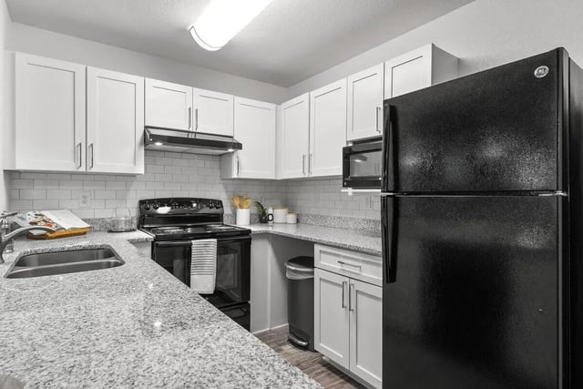 White cabinets black appliances granite counters kitchen at Cabana Beach Gainesville in Gainesville Student Accommodation