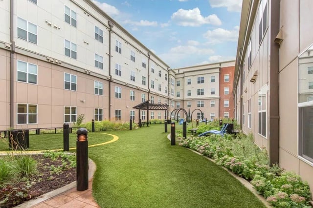 Courtyard with green grass, plants and seating exterior at Landmark Apartment in College Park Student Accommodation