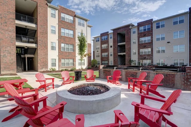 Red chairs around concrete fire pit exterior. at The Reserve at Greensboro in Greensboro Student Accommodation