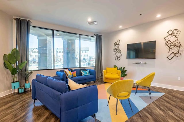 Blue couches yellow chairs geometric wall art living room at Copper Beech Townhomes - San Marcos in San Marcos Student Accommodation