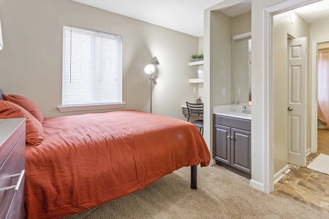 Bed desk vanity sink and doorway bedroom and bathroom at West Quad Greensboro in Greensboro Student Accommodation