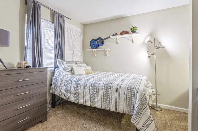 Bed dresser guitar NFL football and plant bedroom at West Quad Greensboro in Greensboro Student Accommodation