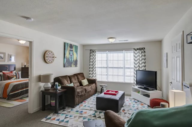 Sofa ottoman TV colorful rug bedroom visible living room at Grove at Huntsville in Huntsville Student Accommodation