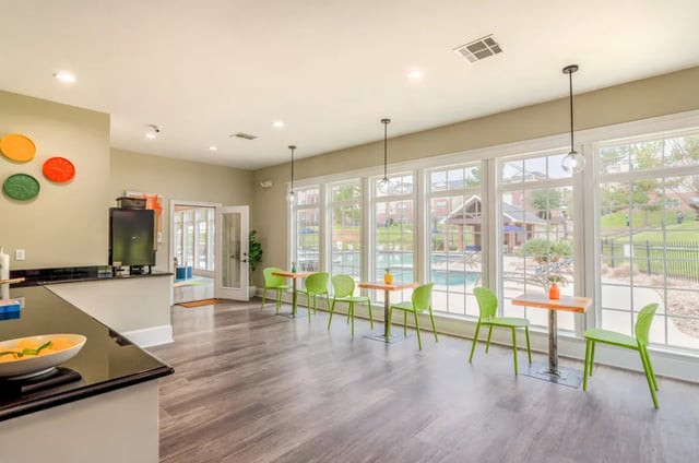Green chairs and tables by large windows Pool area exterior at Grove at Huntsville in Huntsville Student Accommodation