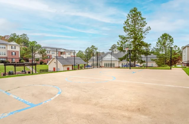 Outdoor basketball court with hoop and buildings exterior at Grove at Huntsville in Huntsville Student Accommodation
