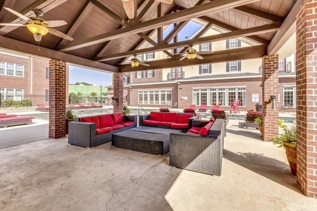 Red couches and black wicker furniture outdoor seating area at The Arch at Denton in Denton Student Accommodation