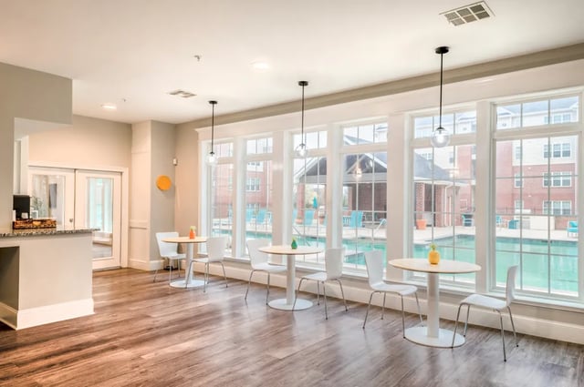 Round tables white chairs pool view common area at The Arch at Denton in Denton Student Accommodation