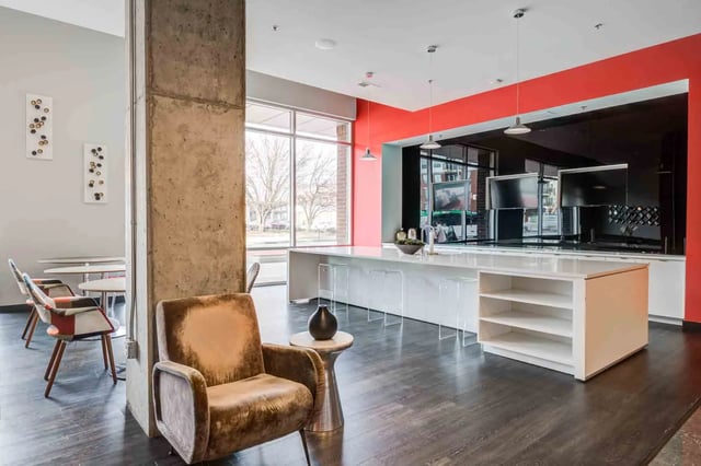 Velvet armchair concrete pillar kitchen island Living room at LUX on Capitol in Indianapolis Student Accommodation