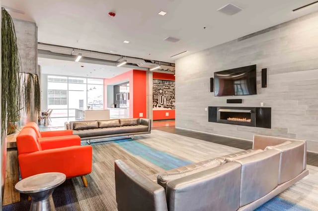 Orange chairs leather sofa fireplace and TV living room at LUX on Capitol in Indianapolis Student Accommodation