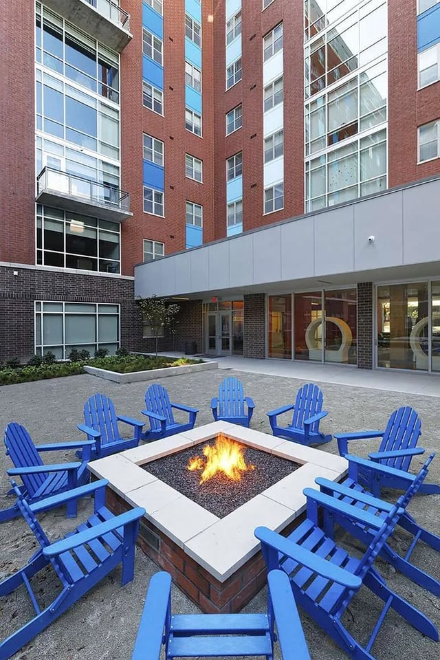 Blue Adirondack chairs surround a square fire pit exterior at LUX on Capitol in Indianapolis Student Accommodation