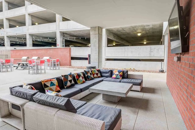 Large sectional sofa concrete table colorful pillows patio area at LUX on Capitol in Indianapolis Student Accommodation