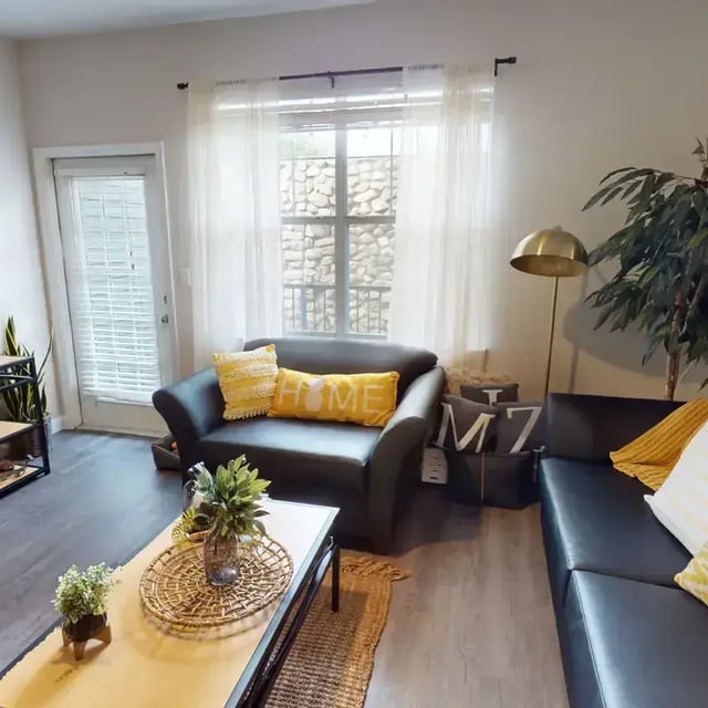 Black sofas yellow pillows coffee table living room at The Quarters at Columbia in Columbia Student Accommodation