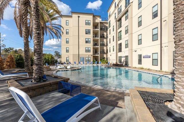 Pool with lounge chairs and palm trees exterior at Ion Baton Rouge in Baton Rouge Student Accommodation