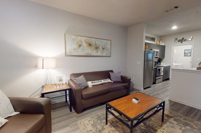 Brown sofas coffee table and kitchen living room at The Quarters at Oxford in Oxford Student Accommodation