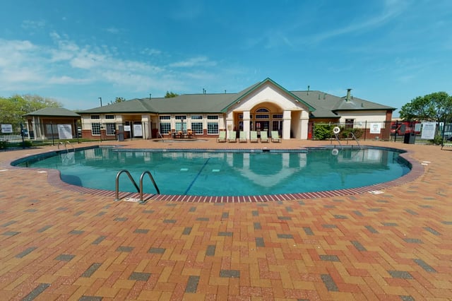 Blue pool with lounge chairs and building exterior at The Quarters at Lincoln in Lincoln Student Accommodation